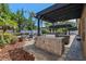 Covered outdoor kitchen with a built-in grill, stone counters, and patio furniture surrounded by lush greenery at 2456 Northumbria Dr, Sanford, FL 32771