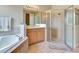 Bright bathroom features a garden tub, glass shower, and single sink vanity for a relaxing and luxurious experience at 2631 Captains Ct, Kissimmee, FL 34746