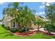 Landscaped front yard with palms and manicured bushes leading to a tan two-story home with a tile roof and paver driveway at 2631 Captains Ct, Kissimmee, FL 34746