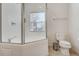 Bright bathroom featuring a glass-enclosed shower, toilet, and a window for natural light at 2745 Corvette Ln, Kissimmee, FL 34746