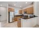 Well-lit kitchen featuring stainless steel refrigerator, wood cabinets, and black countertops at 2745 Corvette Ln, Kissimmee, FL 34746