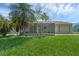 The backyard showcases lush greenery, a screened-in porch, and the exterior of the home at 300 Florida Pkwy, Kissimmee, FL 34743
