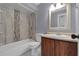 Neutral bathroom features a tub-shower, decorative tile, and wood vanity with a cream colored sink at 300 Florida Pkwy, Kissimmee, FL 34743