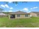 Backyard of the house with a screened porch, green grass, and a view of the surrounding greenery and neighboring homes at 3235 Utah Dr, Deltona, FL 32738