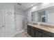 Bathroom with a double sink vanity, granite counters, walk-in shower, and a large mirror showing a walk-in closet at 3235 Utah Dr, Deltona, FL 32738