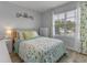 Cozy bedroom with natural light features a floral-patterned quilt, complemented by light grey walls and wood-look floors at 3235 Utah Dr, Deltona, FL 32738