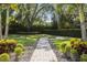 A serene backyard featuring a stone pathway, lush landscaping, and privacy hedge at 3428 Chaine Du Lac Blvd, Windermere, FL 34786