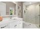 Bright bathroom featuring a walk-in shower with glass door, marble floors, and a vanity with white countertops at 3428 Chaine Du Lac Blvd, Windermere, FL 34786