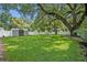 Expansive backyard featuring lush green grass, mature trees, a storage shed, and a white fence at 727 Seminole Ave, Orlando, FL 32804