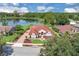 Aerial view of a single-Gathering home with a red tile roof, overlooking a peaceful lake and lush green landscaping at 736 Timacuan Blvd, Lake Mary, FL 32746