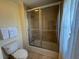 Bright bathroom features neutral tiling, glass shower doors, and a tub with shower head at 7651 Whisper Way # 201, Kissimmee, FL 34747