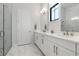 This bathroom offers dual sinks, white cabinets, quartz countertops, and marble tile flooring and shower at 8113 Via Vittoria Way, Orlando, FL 32819