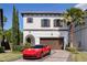 Elegant two-story home with a red tile roof, beautiful landscaping, brick driveway, and a red Ferrari in front at 8113 Via Vittoria Way, Orlando, FL 32819
