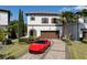 Elegant two-story home with a red tile roof, beautiful landscaping, brick driveway, and a red Ferrari in front at 8113 Via Vittoria Way, Orlando, FL 32819