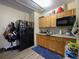 Studio apartment kitchenette with granite countertops, wood cabinets, and a black refrigerator at 874 Brevard Ct, Orlando, FL 32822