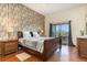 Bedroom featuring a wood-accent wall, dark wood furniture, and sliding glass door to the balcony at 9051 Treasure Trove Ln # 505, Kissimmee, FL 34747
