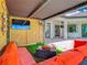Cozy outdoor lounge with an orange couch, artificial turf, mounted TV and decorative lattice wall at 9942 Hatton Cir, Orlando, FL 32832