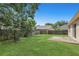 Lush backyard showcasing a green lawn, patio, wooden fence, and shaded by mature trees at 100 Madden Ave, Sanford, FL 32773