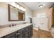 Bathroom featuring granite counters, dual sinks, decorative framed mirror, and tiled shower and floors at 1018 Turner Rd, Winter Park, FL 32789
