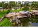 Waterfront property featuring a dock and boat lift, surrounded by lush greenery at 1018 Turner Rd, Winter Park, FL 32789