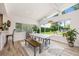 Bright dining area with a farmhouse table, benches, and large windows offering views of the outdoor living space at 1018 Turner Rd, Winter Park, FL 32789