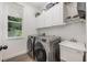 Efficient laundry room with modern washer and dryer, ample cabinet space, a utility sink, and a window at 10241 Pointview Ct, Orlando, FL 32836