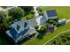 Expansive aerial view of a large, light green house with a detached garage, pool, and green lawn at 10809 Arrowtree Blvd, Clermont, FL 34715