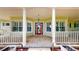 Inviting front porch with classic columns, a red front door, and large windows, providing a warm and welcoming entrance at 10809 Arrowtree Blvd, Clermont, FL 34715