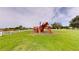 A backyard featuring a wooden playset with vibrant colors set against a backdrop of a white fence and open green space at 10809 Arrowtree Blvd, Clermont, FL 34715