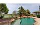 Backyard pool with rock waterfall feature, lush landscaping, and views of the green fields at 10809 Arrowtree Blvd, Clermont, FL 34715