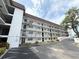 Low angle view of a condo building featuring private balconies, fresh exterior paint and mature trees at 118 S Halifax Ave # 409, Daytona Beach, FL 32118