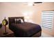 Bedroom with a dark-wood bed frame, side table with a lamp, and a window with a zebra shade at 130 Claire Ln, Davenport, FL 33837