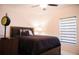 Bedroom with a dark-wood bed frame, side table with a lamp, and a window with a zebra shade at 130 Claire Ln, Davenport, FL 33837