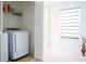 Well-lit laundry room showcasing a washer, storage shelves, and a window with modern blinds at 130 Claire Ln, Davenport, FL 33837