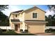 Two-story home featuring a two-car garage, neutral color palette, well-manicured lawn, and a simple front door at 1365 Sawgrass Hammock Ln, Davenport, FL 33837