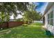 Backyard featuring green grass, brick wall, white fence, and lush trees at 1415 Ellis Fallon Loop, Oviedo, FL 32765
