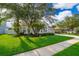 Landscaped front yard featuring lush green grass and mature trees surrounding a gray home at 1415 Ellis Fallon Loop, Oviedo, FL 32765
