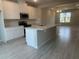 Modern kitchen featuring white cabinets, a large island with a sink, stainless steel appliances, and an open floorplan at 15316 Burgtheater Dr, Winter Garden, FL 34787