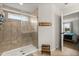Tiled shower in a well-lit bathroom, featuring a step stool and glimpse into the main bedroom at 17416 Painted Leaf Way, Clermont, FL 34714