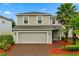 Charming two-story home with a brick driveway, two-car garage, and lush landscaping including palm trees at 17416 Painted Leaf Way, Clermont, FL 34714