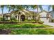 Well-maintained home featuring lush landscaping, a manicured lawn, and mature palm trees enhancing curb appeal at 3307 Kentshire Blvd, Ocoee, FL 34761