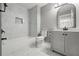 Bathroom with white marble tile, a tub, and a single sink vanity with an arched mirror at 3824 Blue Dasher Dr, Kissimmee, FL 34744