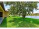 Spacious backyard with lush lawn and mature trees, leading to a tranquil lake at 3904 Coastal Breeze Dr, Kissimmee, FL 34744