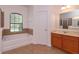 This bathroom offers a tub, cabinet with countertop, and a door, with a window providing natural light at 3904 Coastal Breeze Dr, Kissimmee, FL 34744