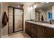 Modern bathroom boasts dual sinks, granite countertops, and a walk-in tile shower with glass door at 5416 Tessin Trl, St Cloud, FL 34771