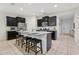 Bright kitchen features stainless steel appliances, dark cabinetry, granite countertops, and a kitchen island with bar seating at 7033 Oakwood St, Davenport, FL 33837