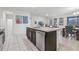 Kitchen island with sink and stainless steel dishwasher, dining area, and a glimpse of the living room at 7033 Oakwood St, Davenport, FL 33837
