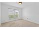 A bright bedroom with a large window, neutral carpet, and minimalist decor at 7744 Country Run Pkwy, Orlando, FL 32818
