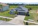 Aerial view showcases a well-maintained gray single-story home with a two-car garage and green surroundings at 7744 Country Run Pkwy, Orlando, FL 32818