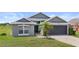 Charming single-story home features a well-maintained lawn, a gray exterior, and a spacious two-car garage at 7744 Country Run Pkwy, Orlando, FL 32818